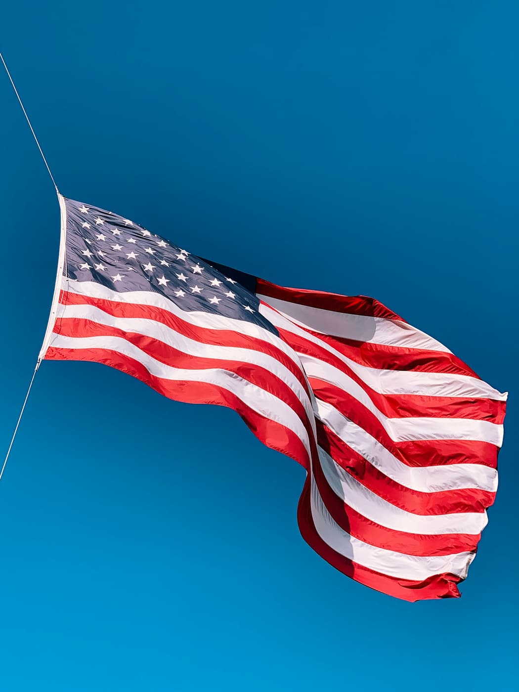 An American flag waving against a blue sky.