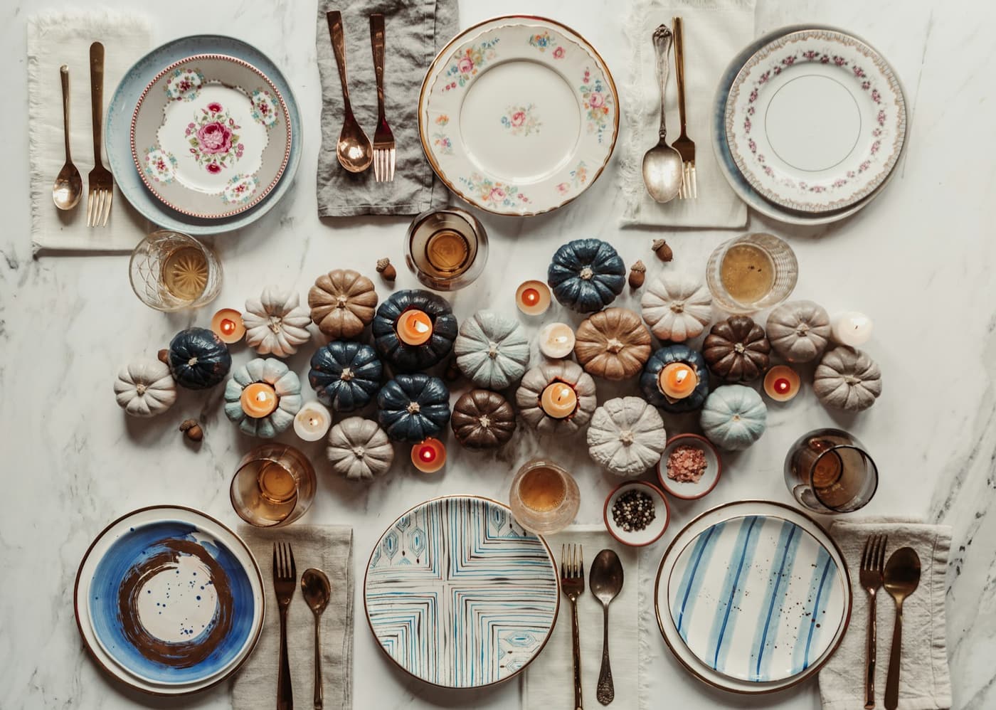 A table set with painted pumpkins between rows of plates.