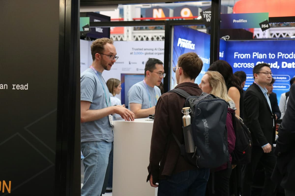 Visitors talking with exhibitors at a busy trade-show booth.