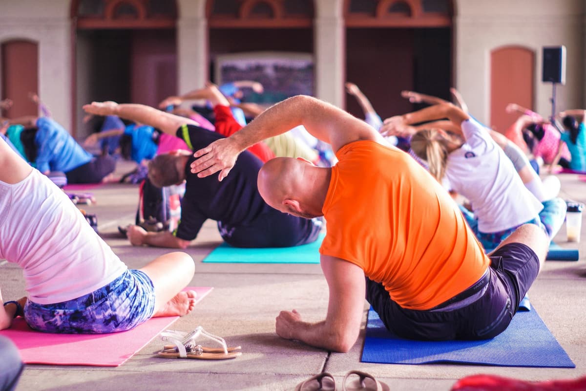A group stretching on mats in a bright fitness class.
